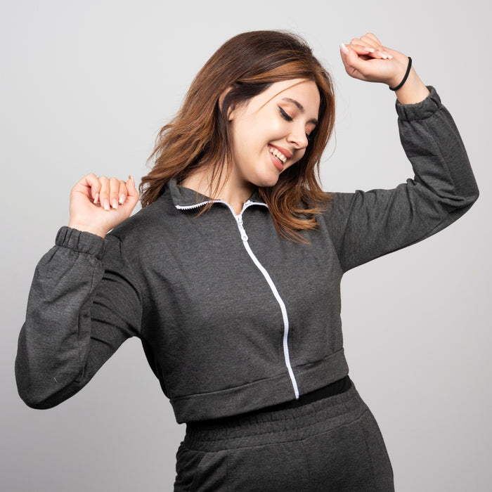 Woman wearing a gray tracksuit with a white zipper on a light gray background