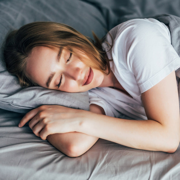 Woman sleeping peacefully on a bed with gray bedding