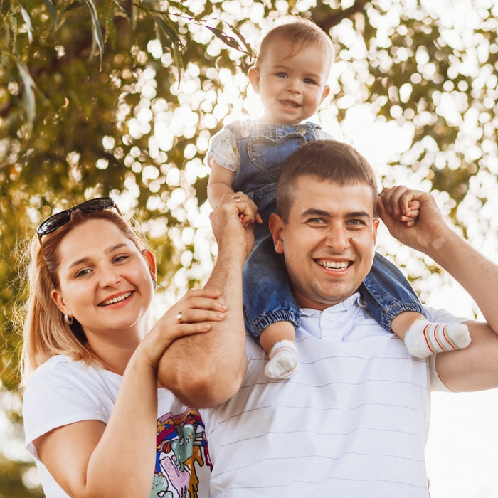 Family of three outdoors with a blurred bokeh background