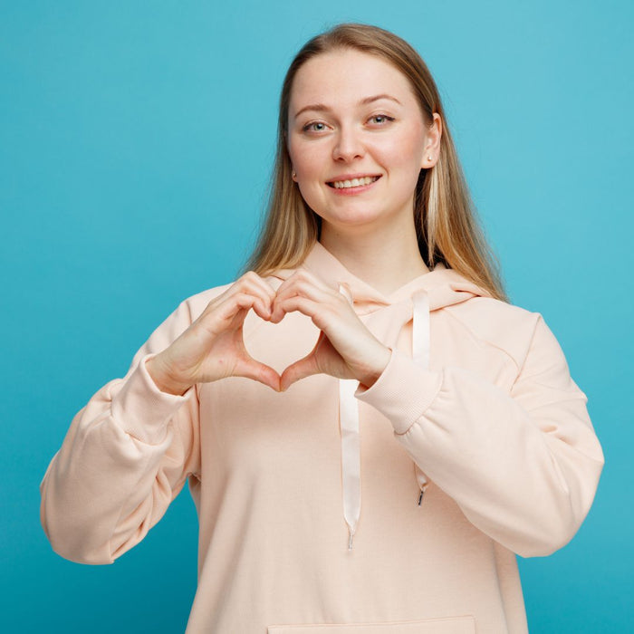 Woman making a heart shape with her hands against a blue background