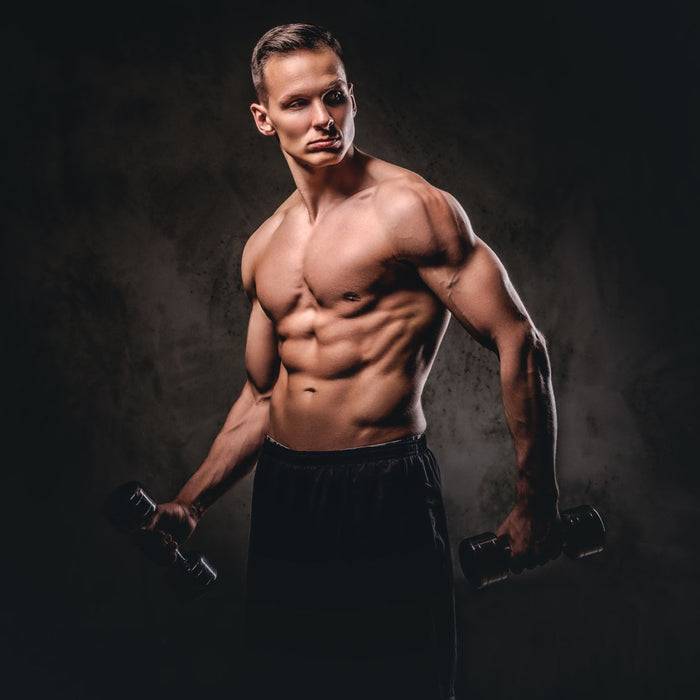 Muscular man holding dumbbells against a dark background