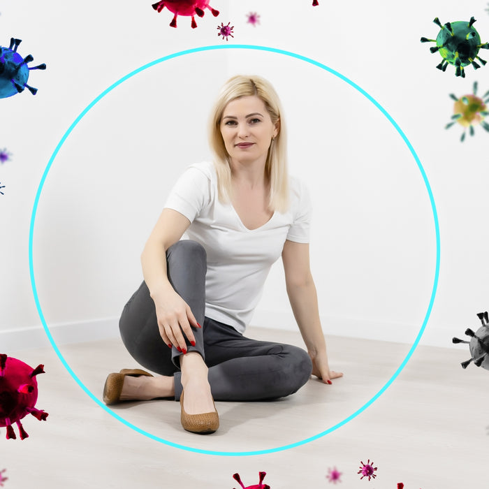 Woman sitting on the floor with a blue circle around her, surrounded by colorful virus illustrations.