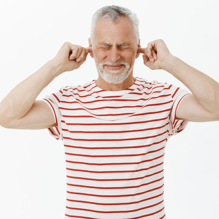 Man in a red and white striped shirt covering his ears on a white background