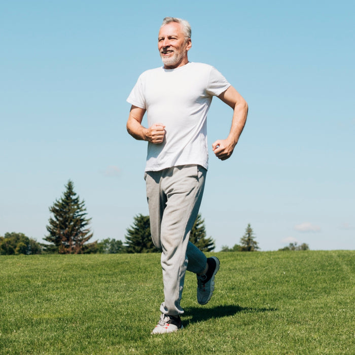 Man running on a grassy hill with a clear blue sky