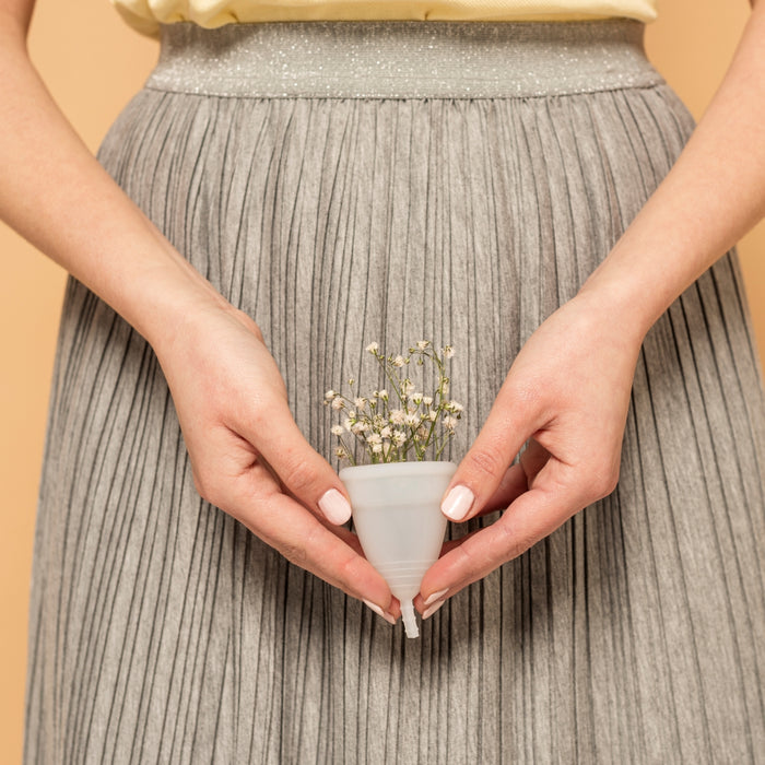 Person holding a small ceramic cup with flowers against a beige background