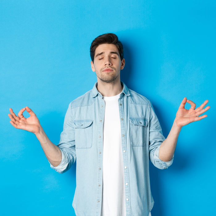 Man in denim shirt and white t-shirt with arms outstretched against a blue background