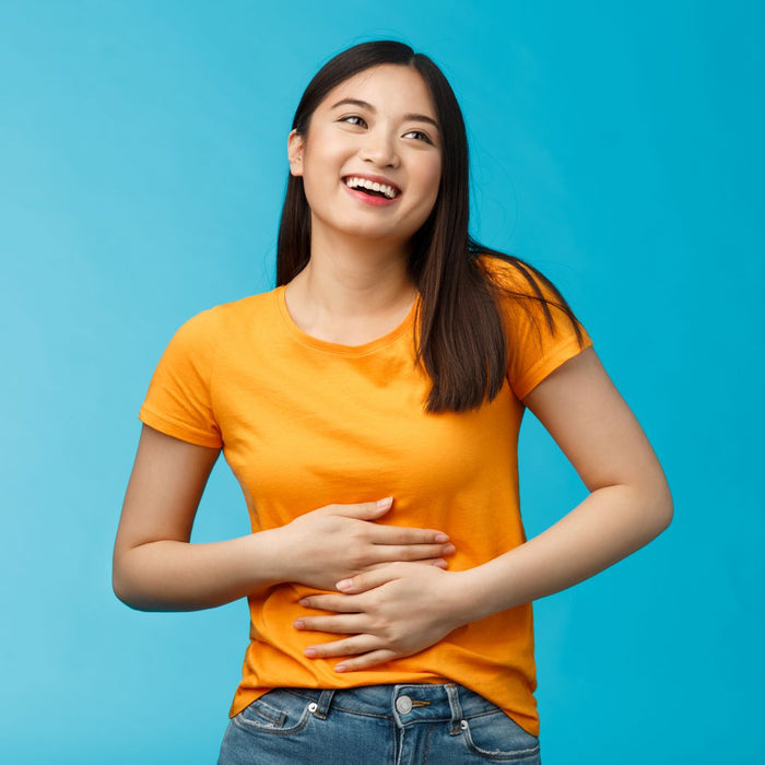 Woman wearing an orange t-shirt and blue jeans against a blue background
