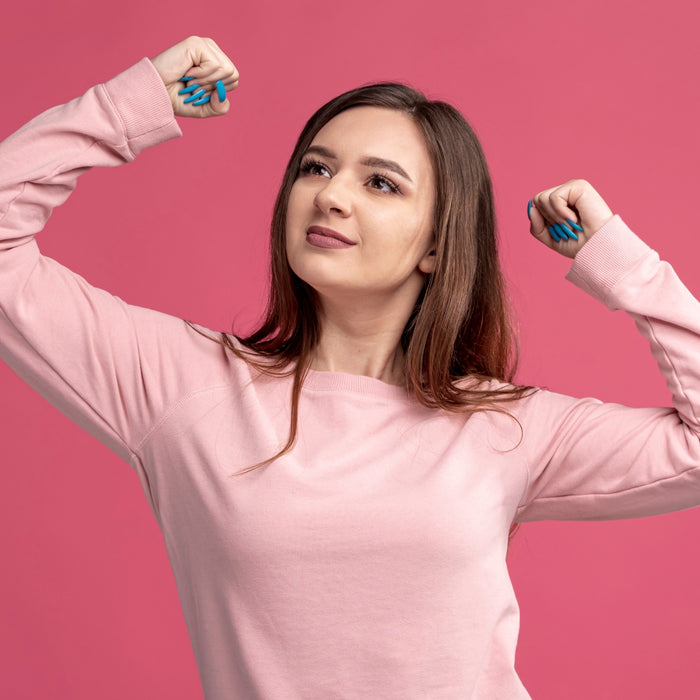 Woman flexing her muscles against a pink background
