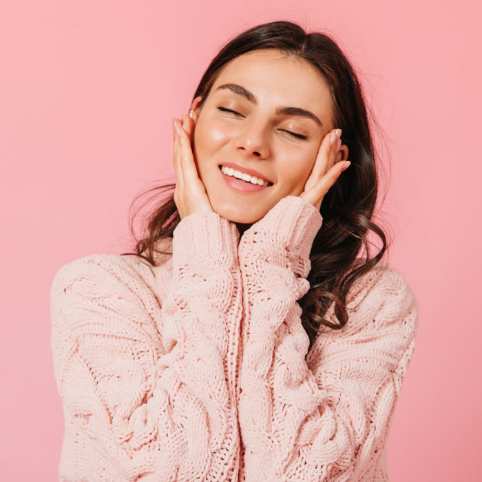 Woman wearing a pink sweater against a pink background