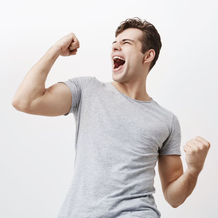 Man in gray t-shirt flexing his arm muscles against a white background