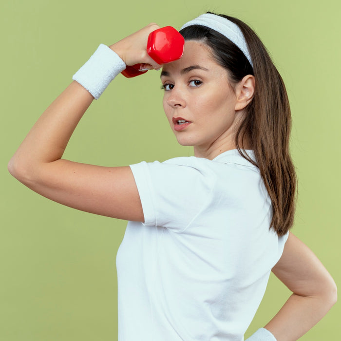 Woman lifting a red dumbbell against a green background