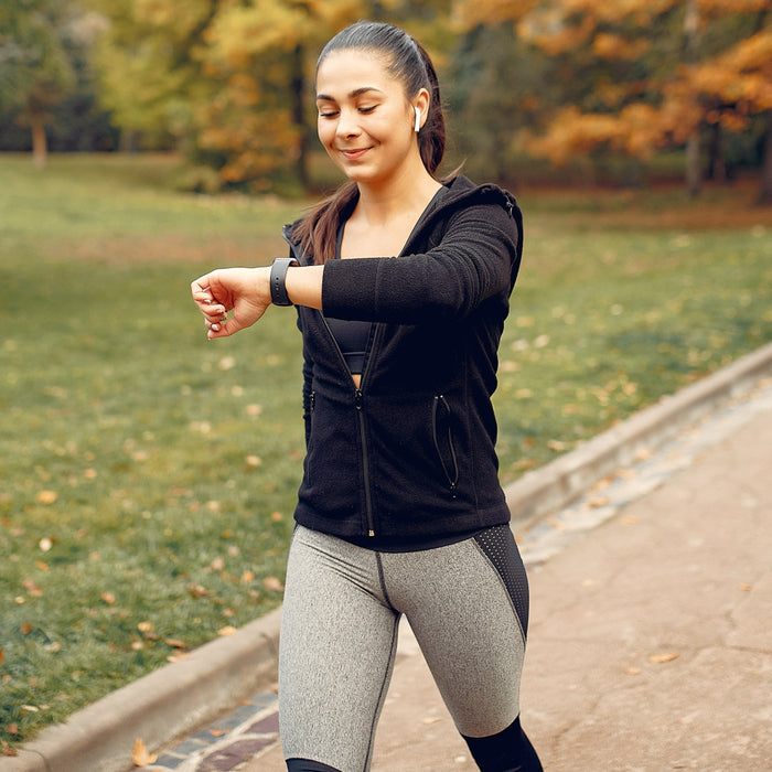 Woman in athletic wear checking her watch outdoors in a park