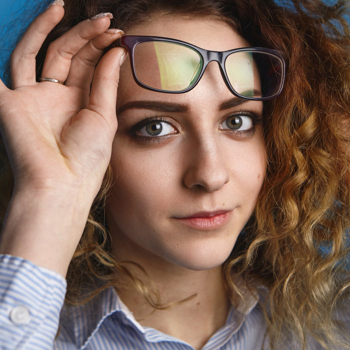 Woman holding a pair of glasses with a blurred background